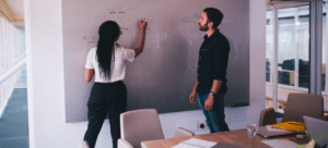 Image of two people at a whiteboard planning